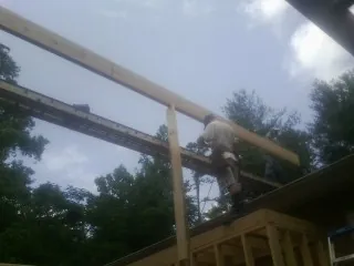 Carpenter setting a ridge beam over a new addition frame — Ice Dam Removal by Roofing Brothers in Keene Valley