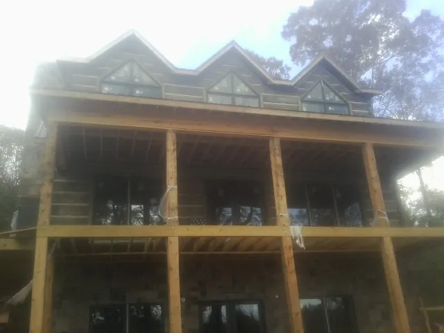 Dormers and porch framing on a large log home under construction — Roof Coating work by our crew in Keene Valley