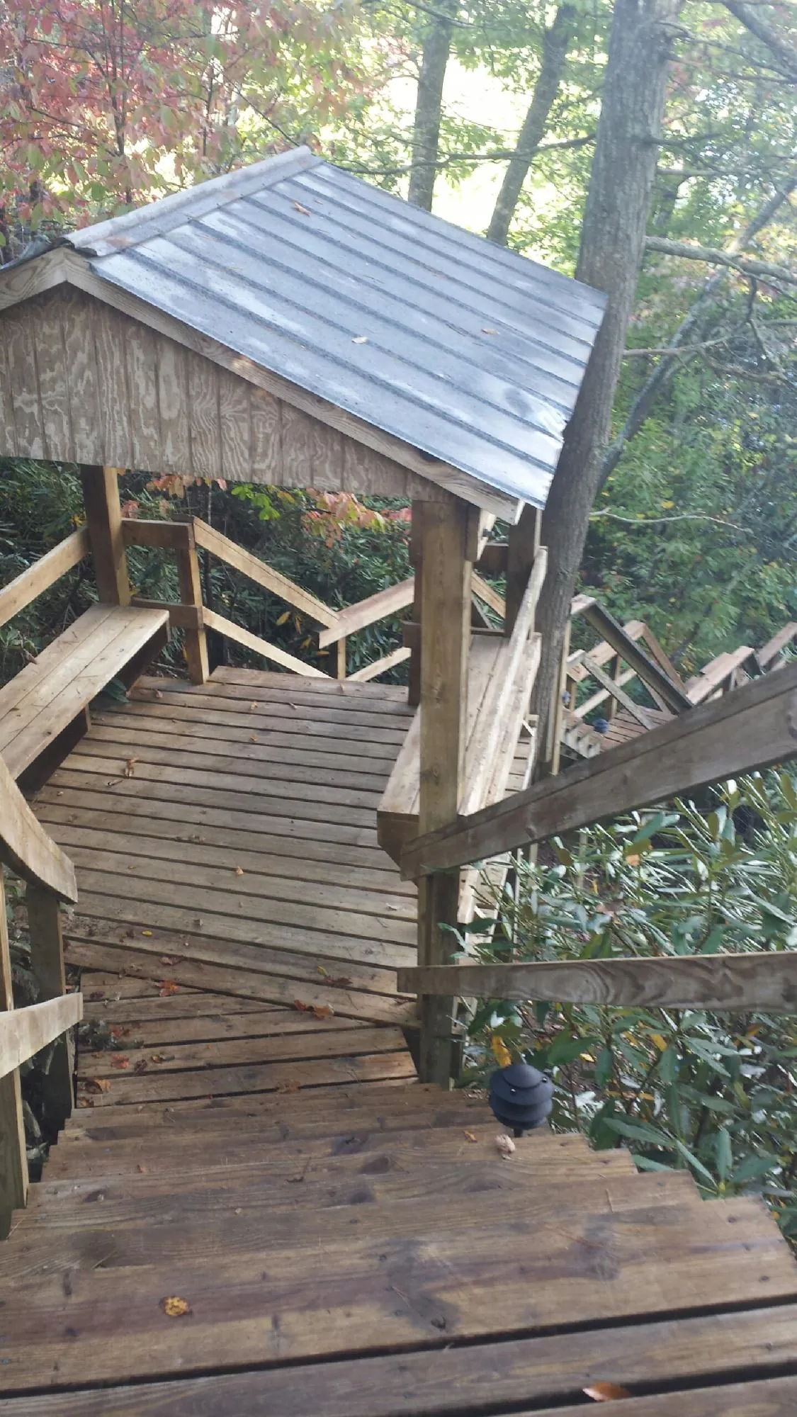 Metal roofed shelter over wooden steps on a wooded walkway — Skylight Repair & Installation work by our crew in Keene Valley