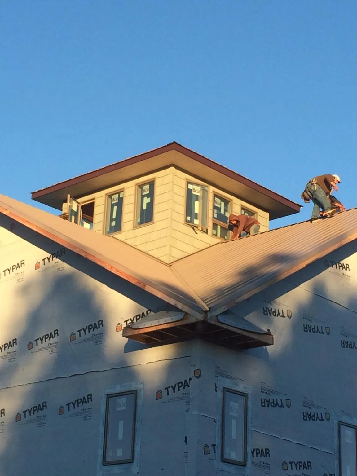 Roofers working around a rooftop cupola on a new metal roof at sunset — Roof Waterproofing in Keene Valley by Roofing Brothers